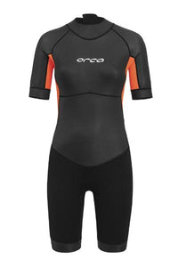 Women's ORCA Vitalis Shorty Wetsuit in black with striking orange hi-vis panels, featuring short sleeves and legs for swimming.